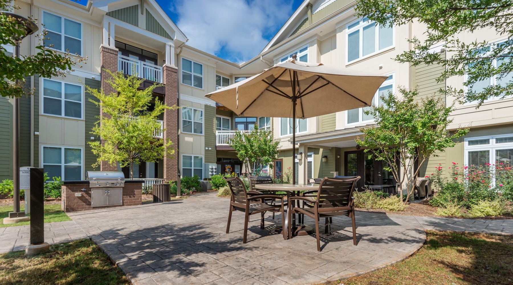 a courtyard with tables, chairs and an umbrella